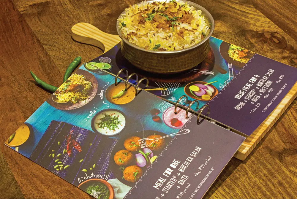 A menu with a bowl of food on top of a wooden table.