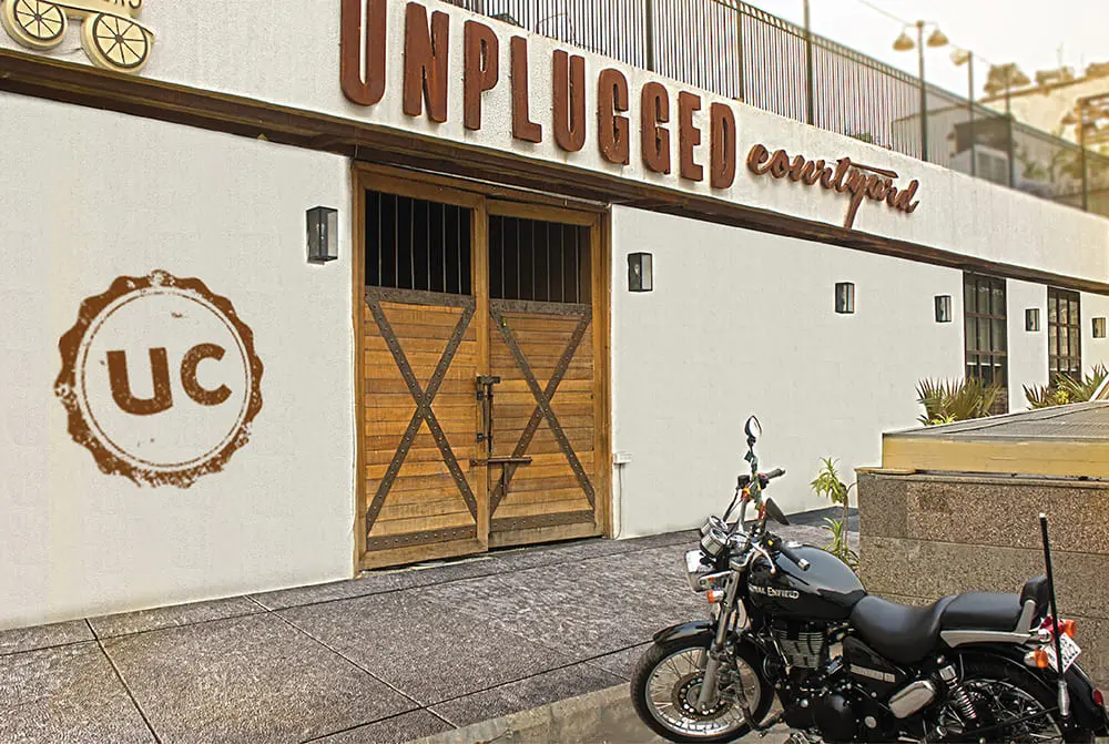 A motorcycle is parked in front of a building that says unplugged.