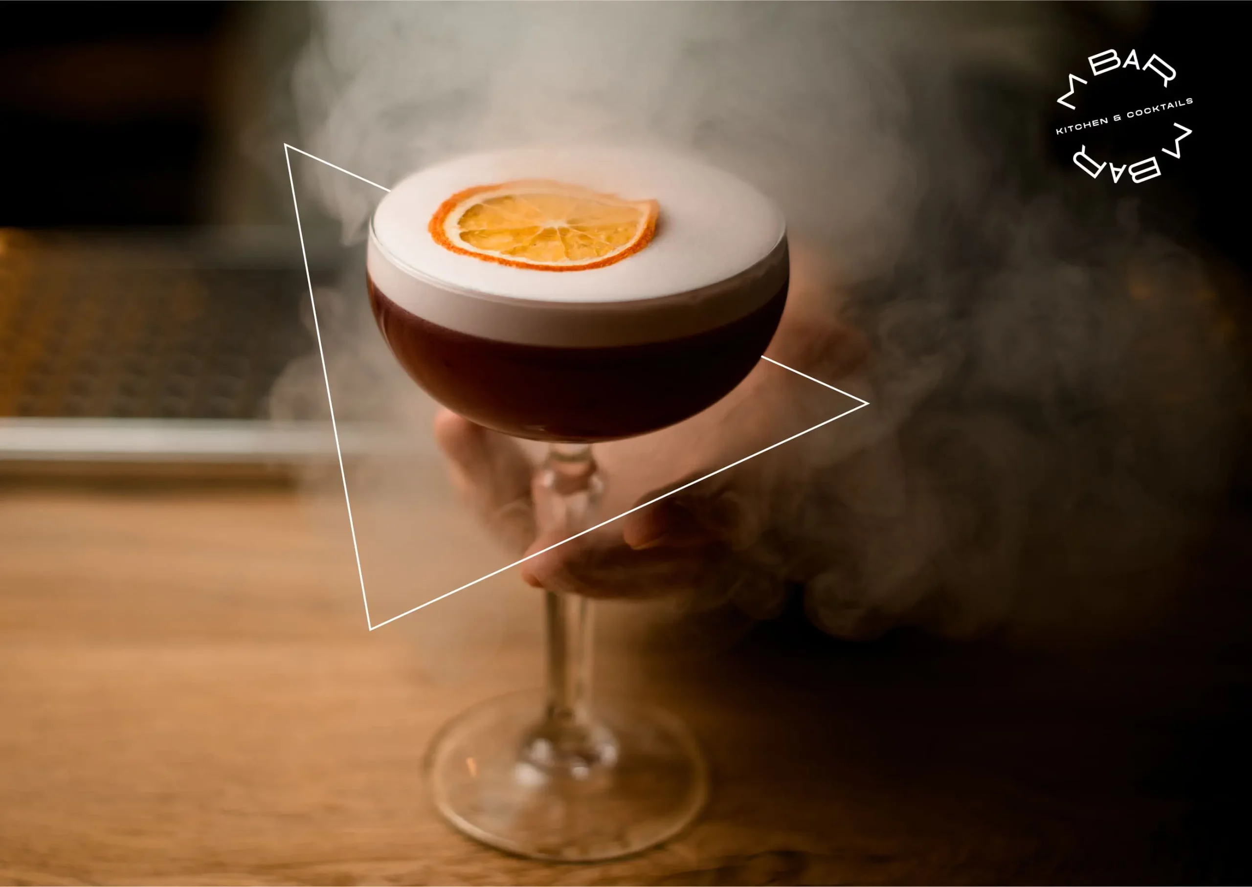 A person holding a cocktail with smoke coming out of it.
