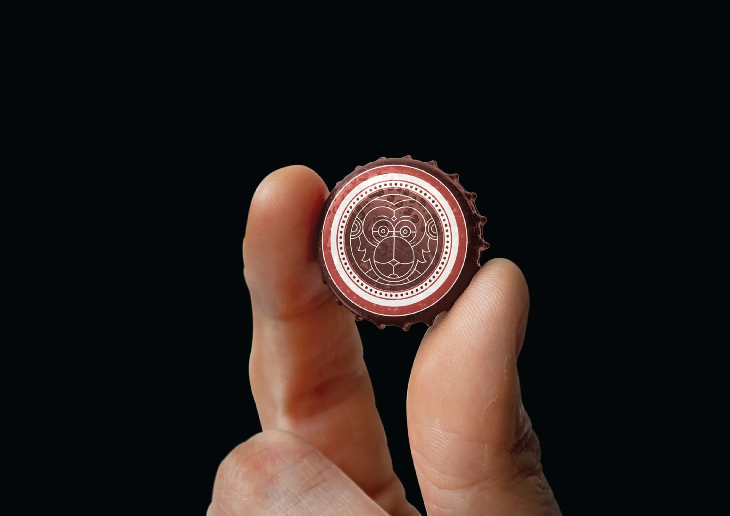 A person's hand holding a bottle cap with a logo on it.