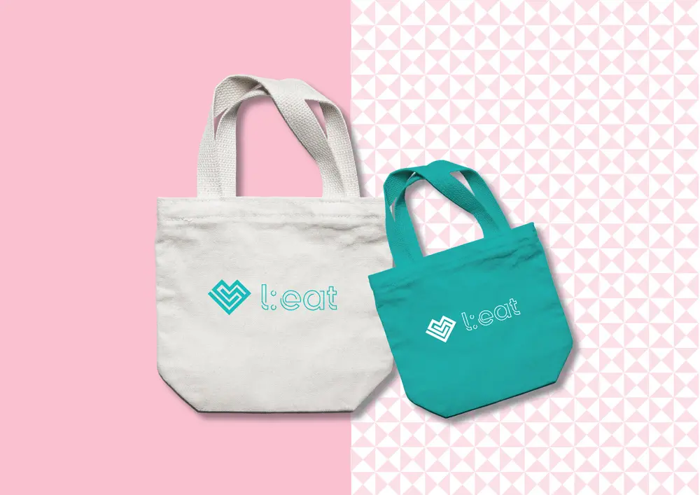 Two tote bags on a pink background.