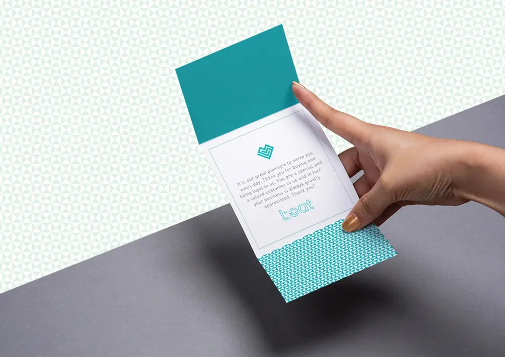 A hand holding up a folded card with a polka dot pattern.