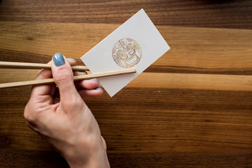 A person holding chopsticks while holding a piece of paper.