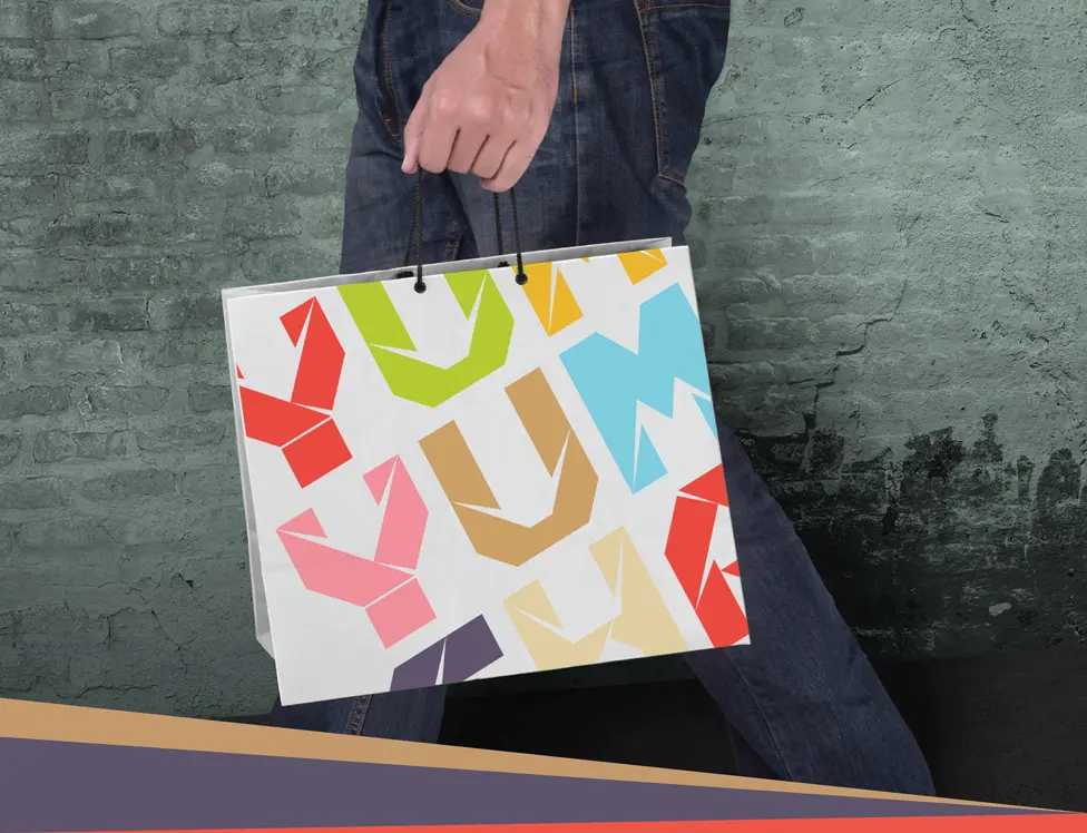 A man is carrying a shopping bag with a colorful design.