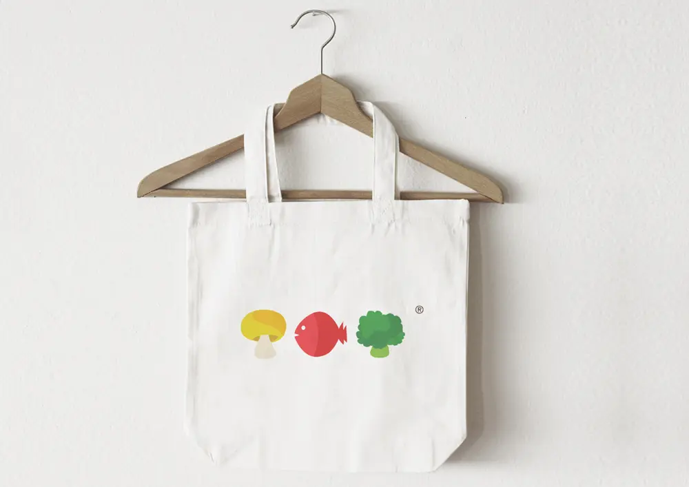 A white tote bag with colorful vegetables on it.