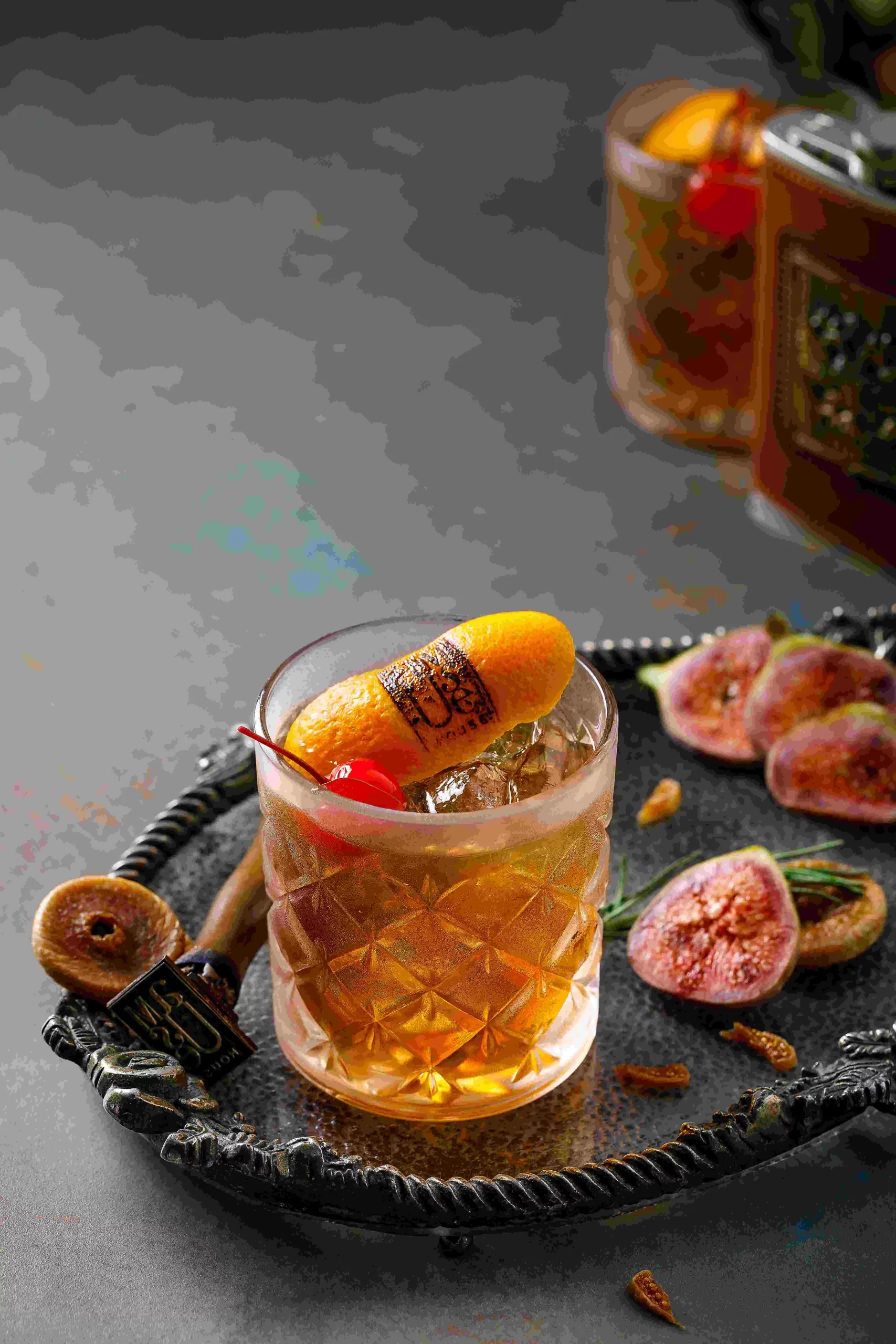 A cocktail with figs and oranges on a tray.