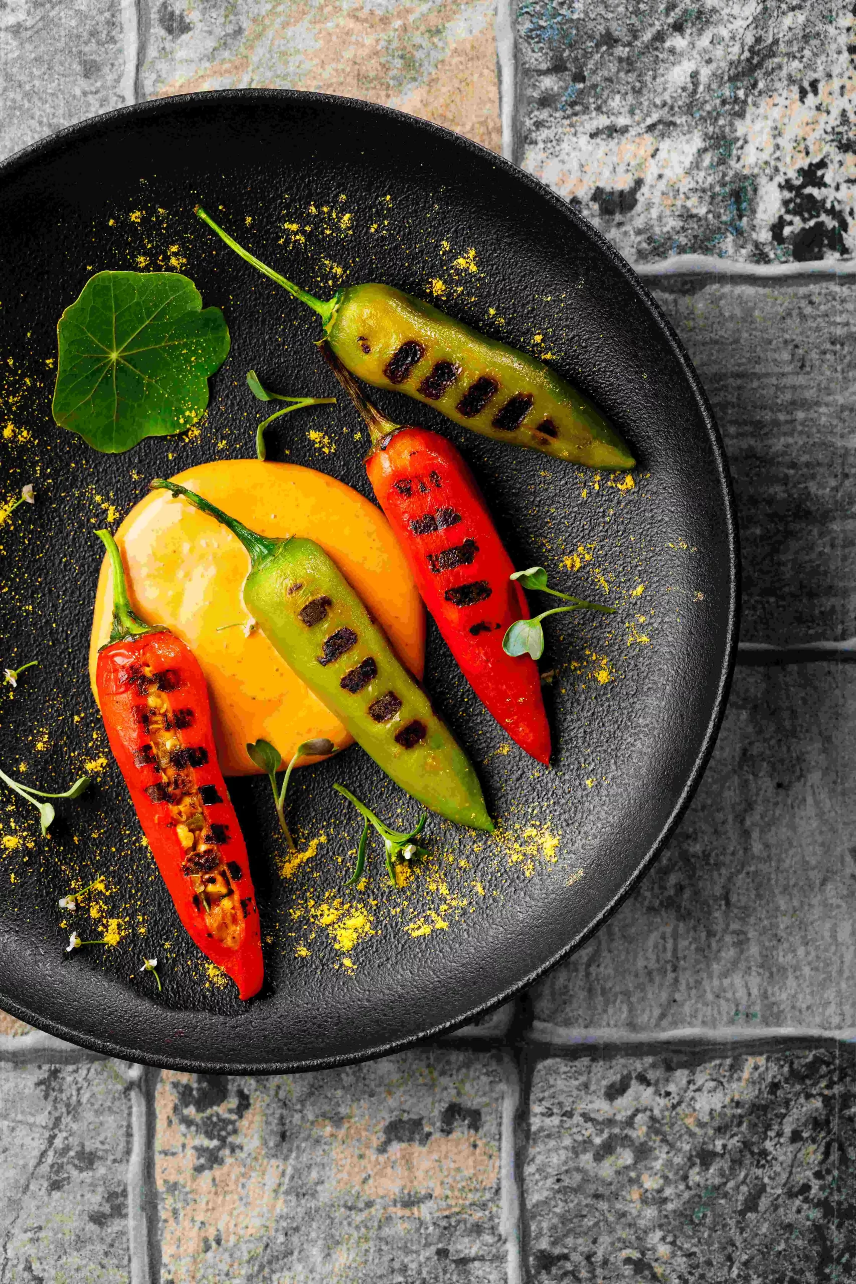 Grilled peppers on a black plate.