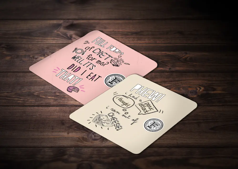Two coasters on a wooden table with doodles on them.