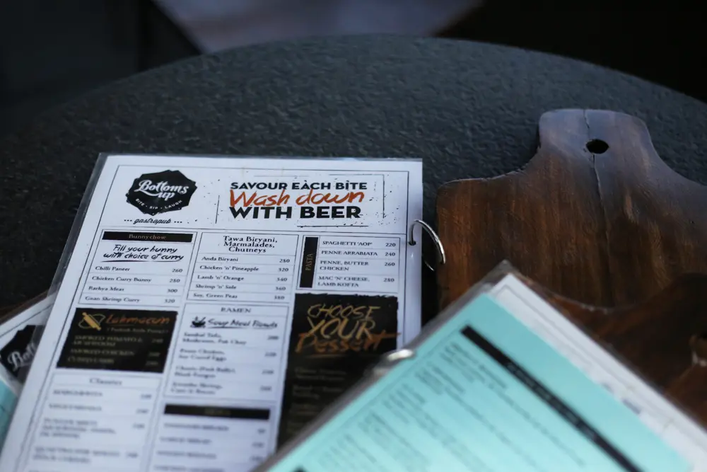 A menu is sitting on a table next to a bottle of beer.