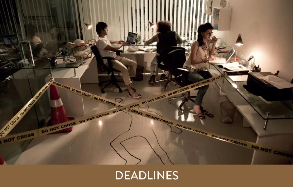 A group of people sitting at a desk with the words deadlines.