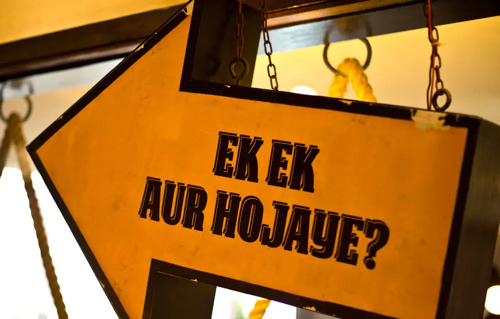 A sign hanging from a door that says ex aur hoojaye?.