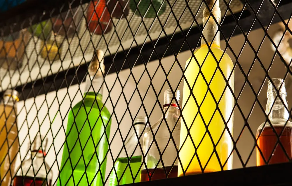 A bar with bottles of different colors behind a wire mesh.