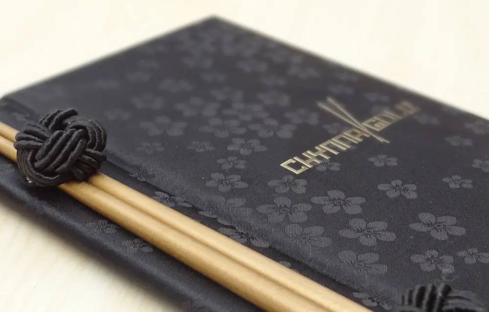 A black book with chopsticks on top.