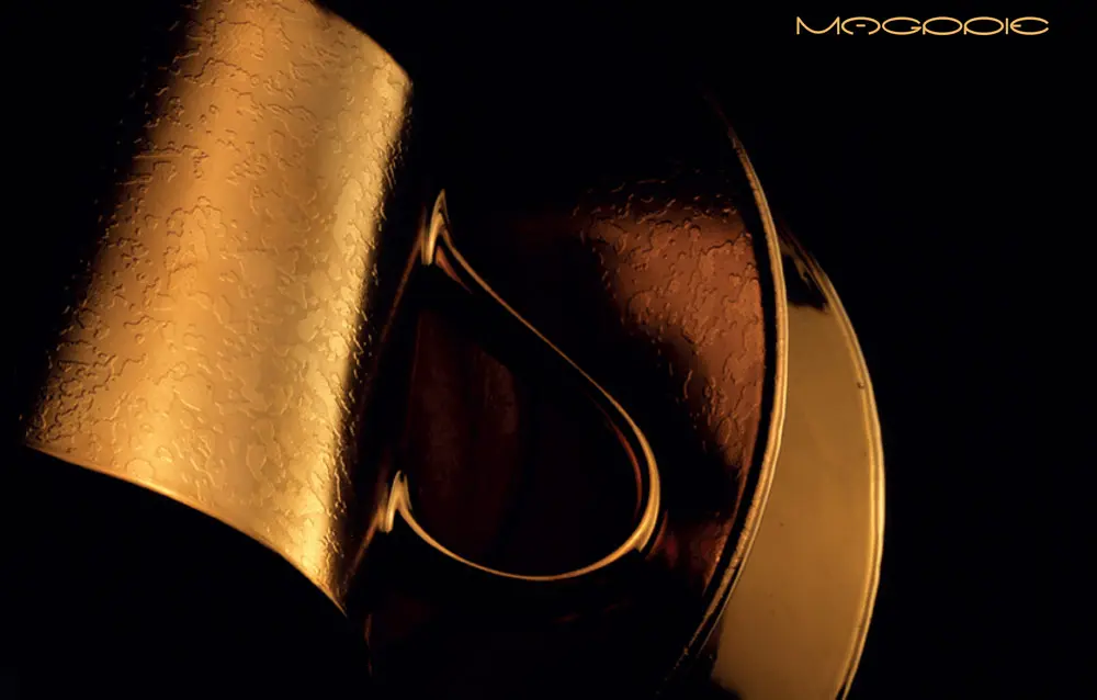 A close up of a gold cup on a black background.