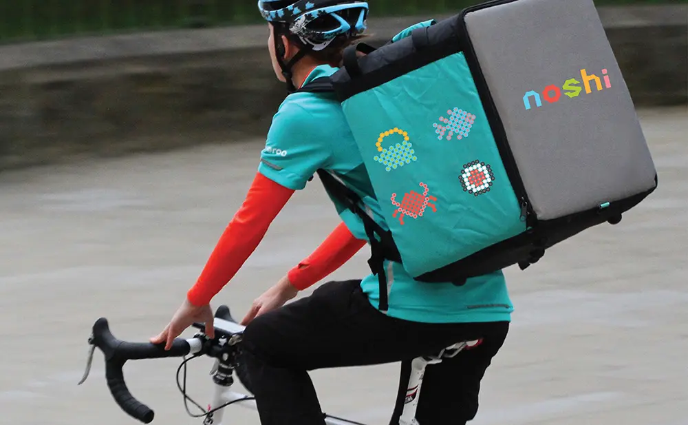 A man riding a bike with a bag on his back.